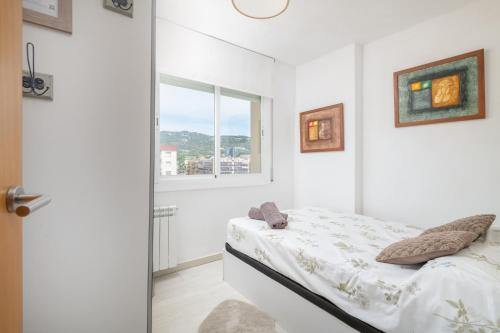 a white bedroom with a bed and a window at Playa 5 min, Terraza, AC, WiFi, Parking in Calella