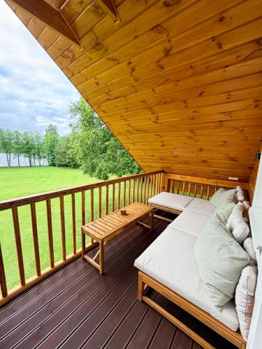 a porch with two beds and a bench on a deck at Lake Lodge Labanoras in Šnioriškės