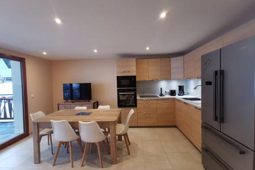 a kitchen with a wooden table and white chairs at L'écrin des neiges - Sauna in La Féclaz