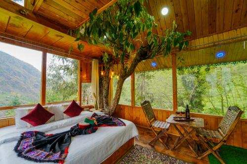 a bedroom with a bed and a tree in it at Himalayan Abode Tree House in Sainj