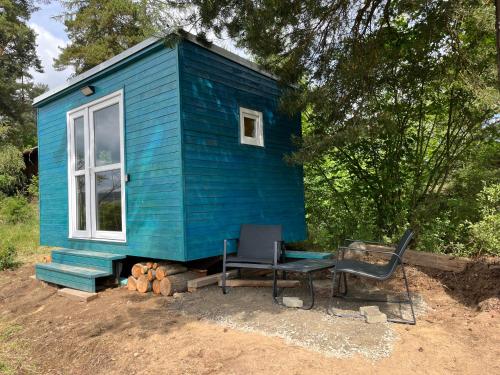 a blue tiny house with a table and a chair at Samoobslužná maringotka in Žihobce