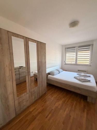 a bedroom with a large bed and a mirror at Apartman Enigma II in Ruma