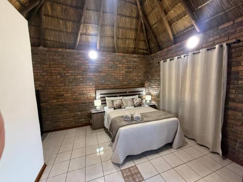 a bedroom with a bed and a brick wall at The Willows in Polokwane