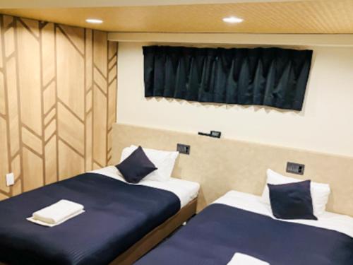 two beds in a small room with a window at HOTEL LiVEMAX BUDGET Nippori in Tokyo