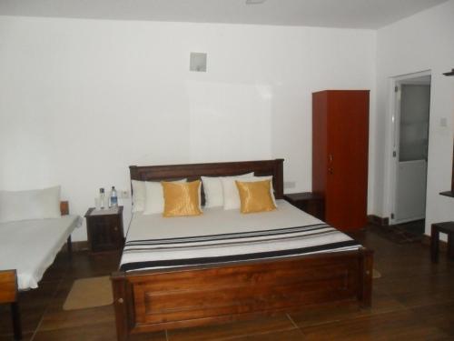 1 dormitorio con 1 cama de madera y 2 almohadas en river edge bungalow, en Matale