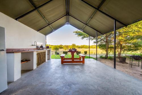 an open kitchen and dining area of a pavilion with a table and chairs at Hakusembe River Camping2Go in Kansukwa