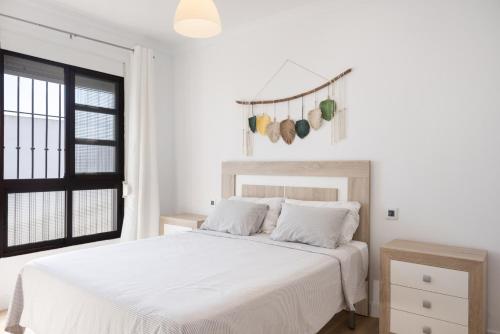 a white bedroom with a white bed and a window at Casapoley Vejer in Vejer de la Frontera