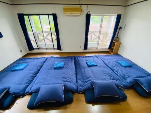 a large blue bed in a room with two windows at Guest House Rakufu in Anan