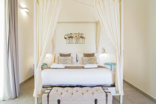 a bedroom with a large white bed with curtains at Pietra Bianca Marzamemi in Marzamemi