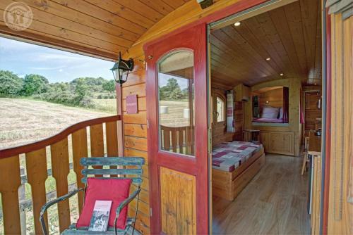 a porch of a train with a bed and a chair at La roulotte à la ferme in Palogneux