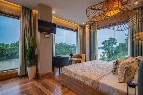 a bedroom with a large bed and large windows at River View Resort in Haridwār
