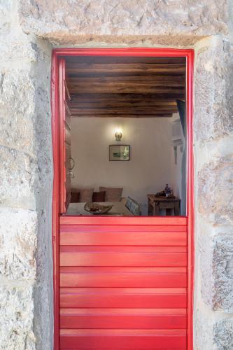 a red garage door in a stone wall at Marketos Traditional Windmill in Tripiti