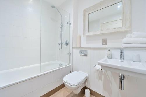 a white bathroom with a toilet and a sink at Porthminster Mews 2 in St Ives