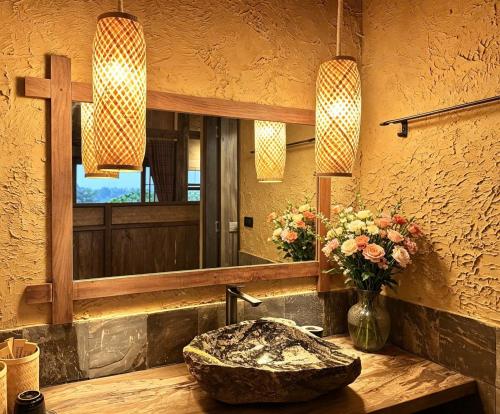 a bathroom with a stone sink and a mirror at The MD Ba Vi Retreat in Ba Vì