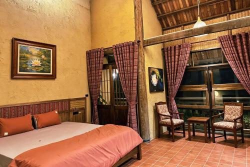 a bedroom with a bed and two chairs at The MD Ba Vi Retreat in Ba Vì