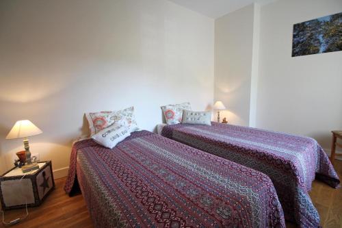 two beds in a room with purple blankets and pillows at La petite ecosse in Châteauneuf-la-Forêt