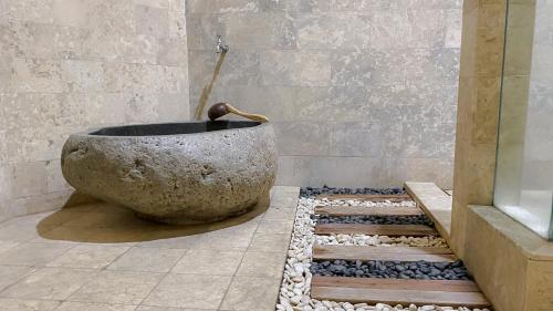 eine Badewanne in einem Badezimmer mit einer Steinschüssel in der Unterkunft Bukit Daun Hotel & Resort in Kedak