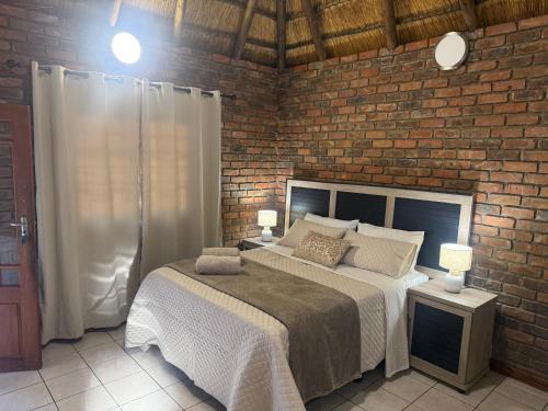 a bedroom with a bed and a brick wall at The Willows in Polokwane