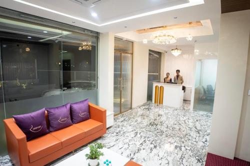 a lobby with a couch and two people at a counter at Ramnaa Hotel in Jāmb