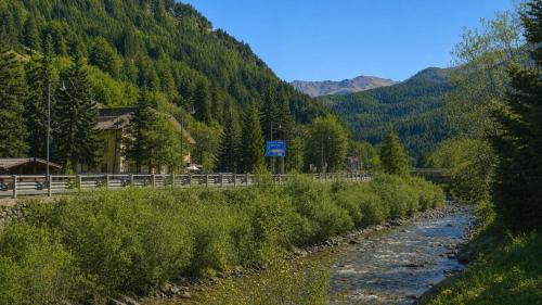 a river next to a road with a mountain at Hostdomus - Petit Bleu in Cesana Torinese