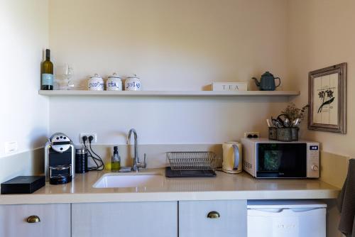 a kitchen counter with a sink and a microwave at The White Chalet Boutique in Moshav Ramot