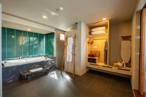 a bathroom with a tub and a large window at Kalima Resort and Spa in Patong Beach