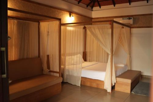 a bedroom with a four poster bed with curtains at Wild Nest Resort, Wayanad in Meppādi