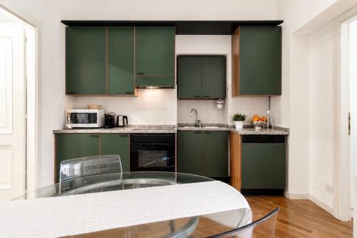 a kitchen with green cabinets and a glass table at Vittorio Emanuele Apartment - Downtown Como in Como