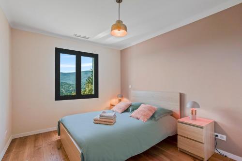 a white bedroom with a bed and a window at Les Oliviers De Lunéa in Fayence