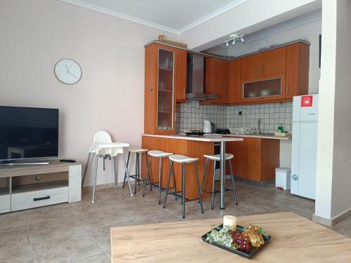 a kitchen with wooden cabinets and a tv and a table at Summer apartment in Nea Peramos