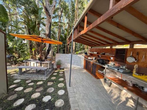 an outdoor kitchen with an umbrella and a table at Kholiwe 1 - 4 sleeper glamping in a forest in Port Edward