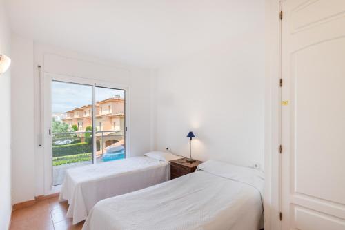 two beds in a room with a large window at Port Pals B202 in Pals