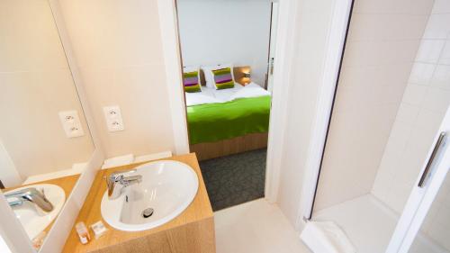 a bathroom with a sink and a shower and a bed at Kloster Heidberg in Eupen