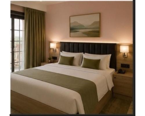 a bedroom with a large white bed with two lamps at Shree Videhi Atithi Grah in Ayodhya