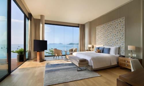 a bedroom with a large bed and a large window at V Villas Phuket - MGallery Collection in Panwa Beach
