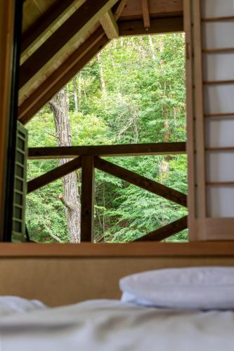 a bedroom window with a view of the forest at 1日1組様限定 最大10名様 キャンプ 温泉付き Villa 水と深緑 in Azumino