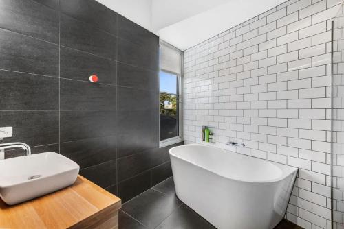 a bathroom with a white tub and a sink at Coastal Tree Top Views in Aireys Inlet