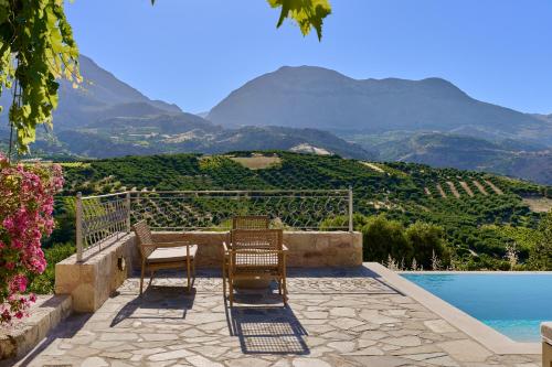 two chairs and a pool with mountains in the background at Villa Iremia in Nísi