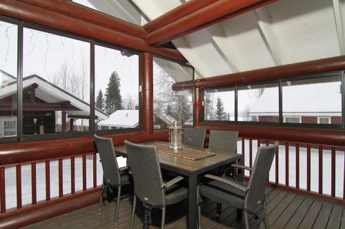 a dining table and chairs on a balcony with windows at Messilä Camping in Hollola