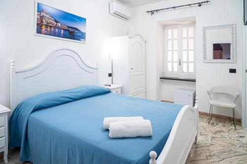 a white bedroom with a blue bed and a chair at Santa Maria Rooms in Santa Maria di Castellabate
