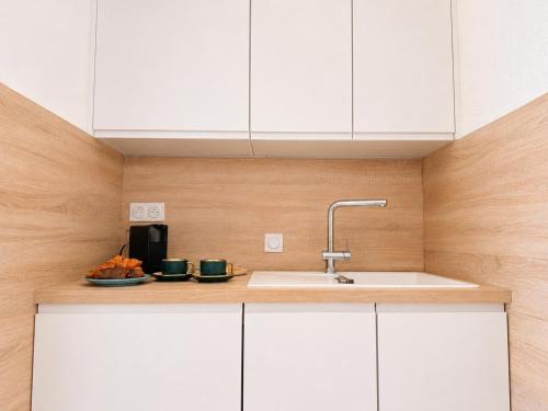 a kitchen with white cabinets and a sink at La Marina Cannes Suites in Mandelieu-La Napoule