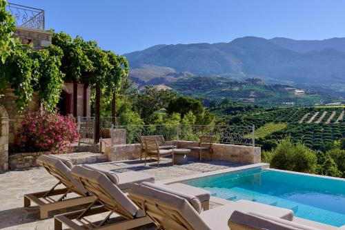 a patio with chairs and a swimming pool with a view of mountains at Villa Iremia in Nísi