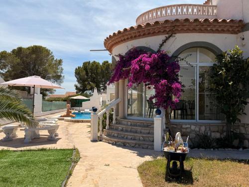 a house with purple flowers on the front of it at Amarella Costa Dorada - Alojamientos privados en villa mediterránea con amplia piscina y zonas BBQ in Les tres Cales