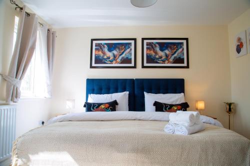 a bedroom with a large bed with a blue headboard at Luxury 2 Bedroom serviced accommodation in Solihull