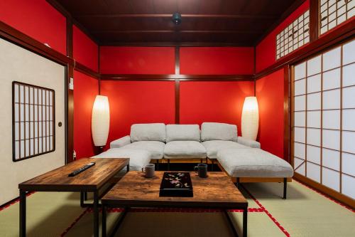 a living room with red walls and white couches at 金沢町家 凛 in Kanazawa
