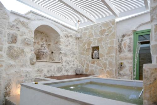 a bath tub in a room with a stone wall at Borgo Pascarosa in Ostuni