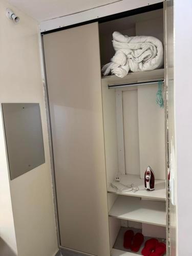 a small white closet with towels and red shoes at Sunrise Hills BNB in Ngong
