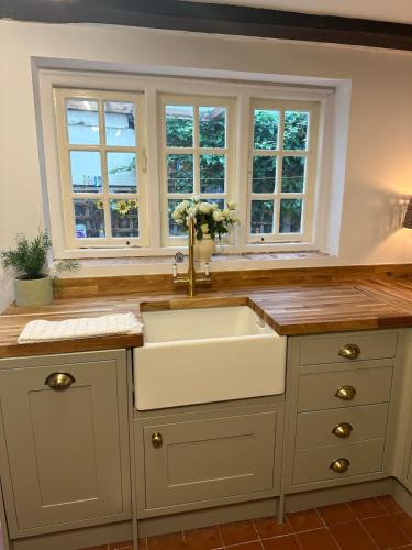 a kitchen with a sink and two windows at Spring Cottage in Hoylake