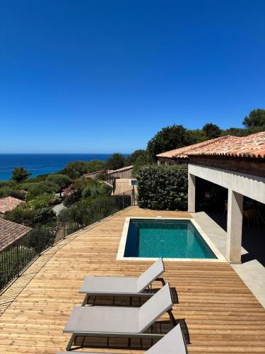 a swimming pool on a wooden deck with a view of the ocean at Résidence La Plage in Propriano