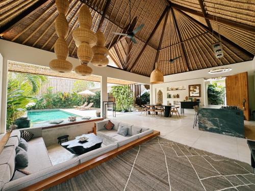 an open living room with a couch and a pool at Villa Caz a Bali in Canggu